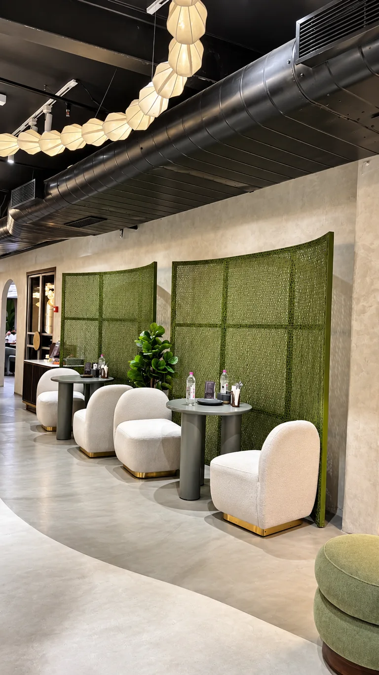 Curved olive green woven partition screens with low ivory bouclé lounge chairs and modern marble pedestal tables under warm ambient paper lanterns.